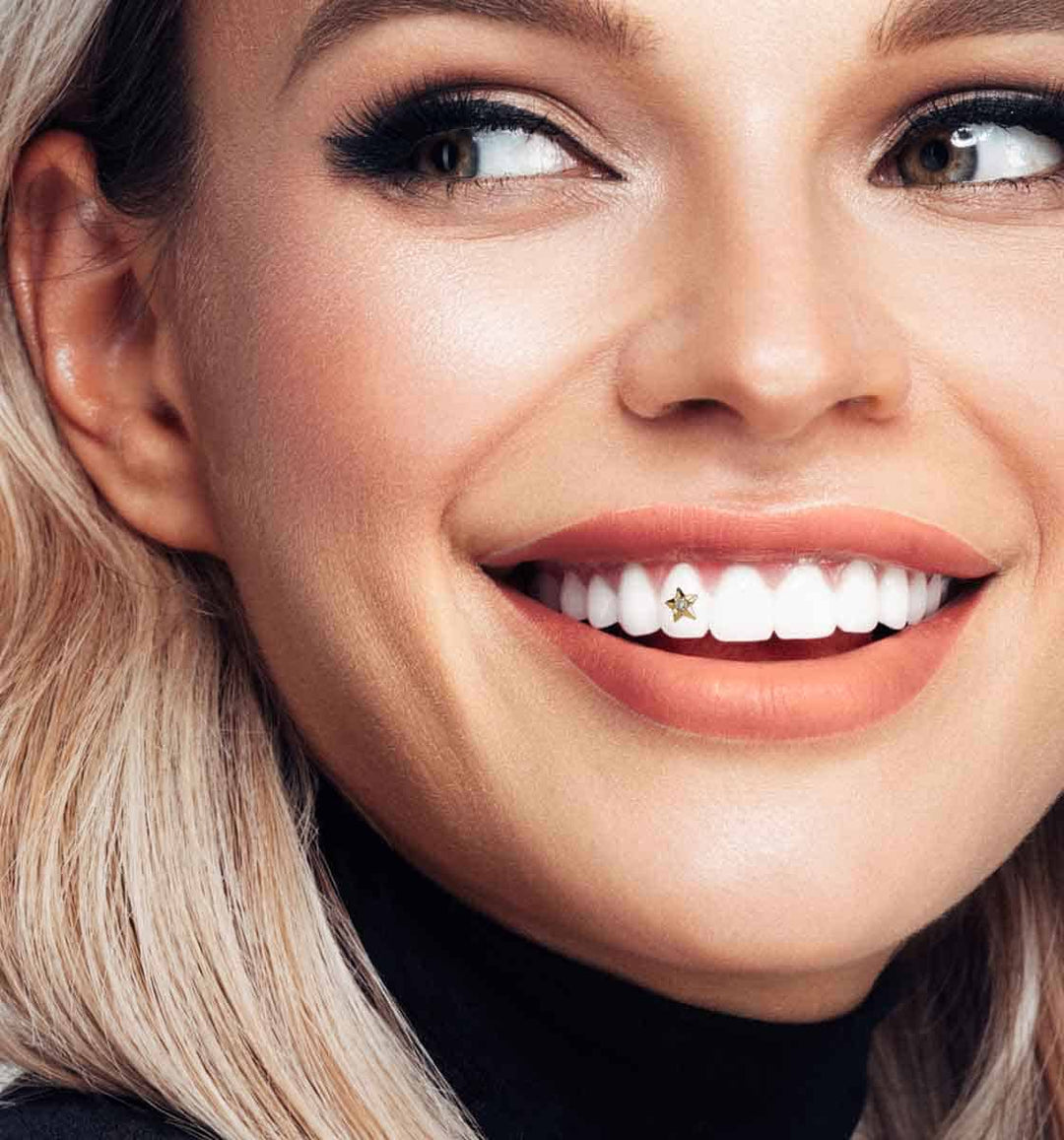 Close-up of a smiling woman with a 22k gold tooth gem set with a small diamond